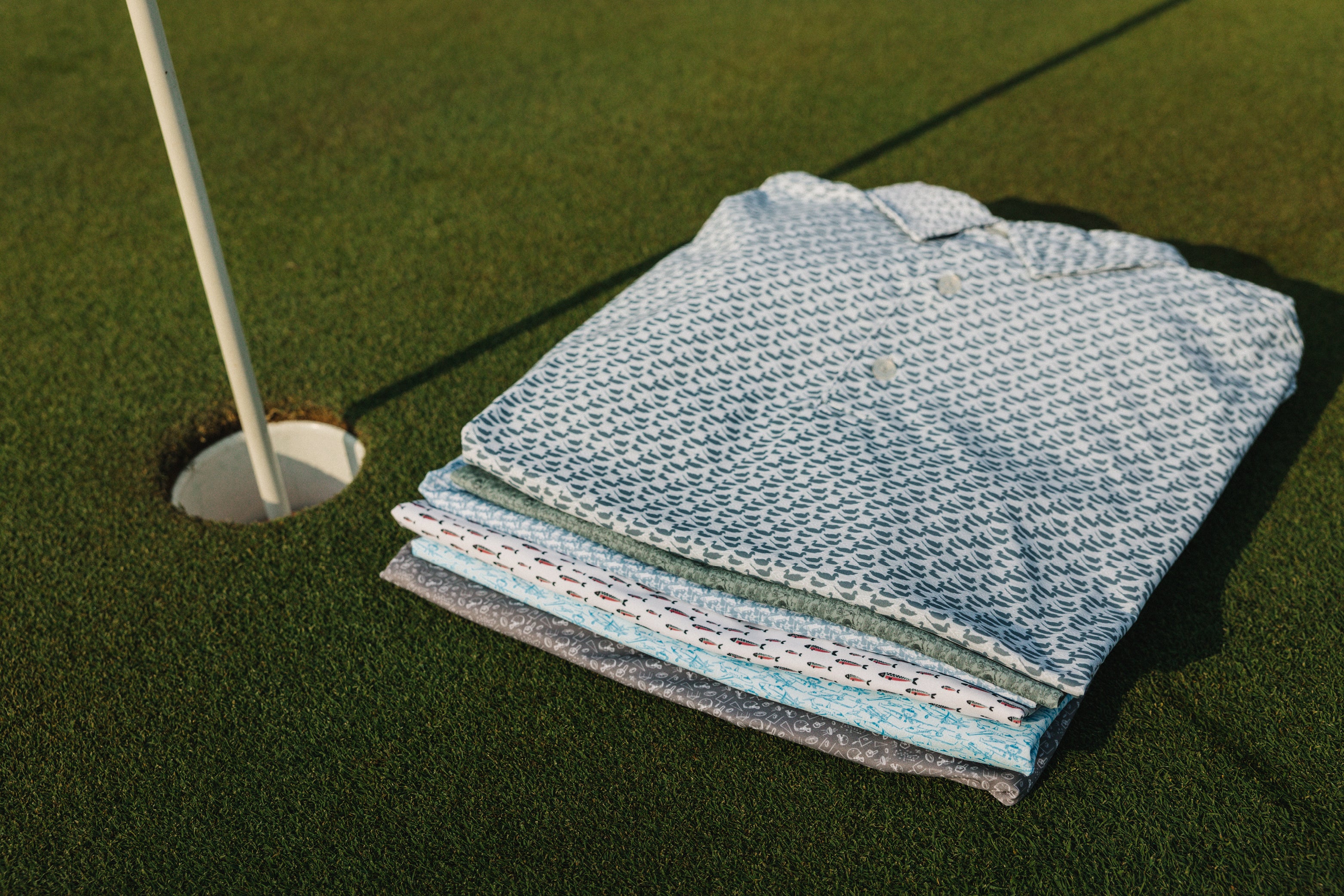 performance polos stacked on a golf green