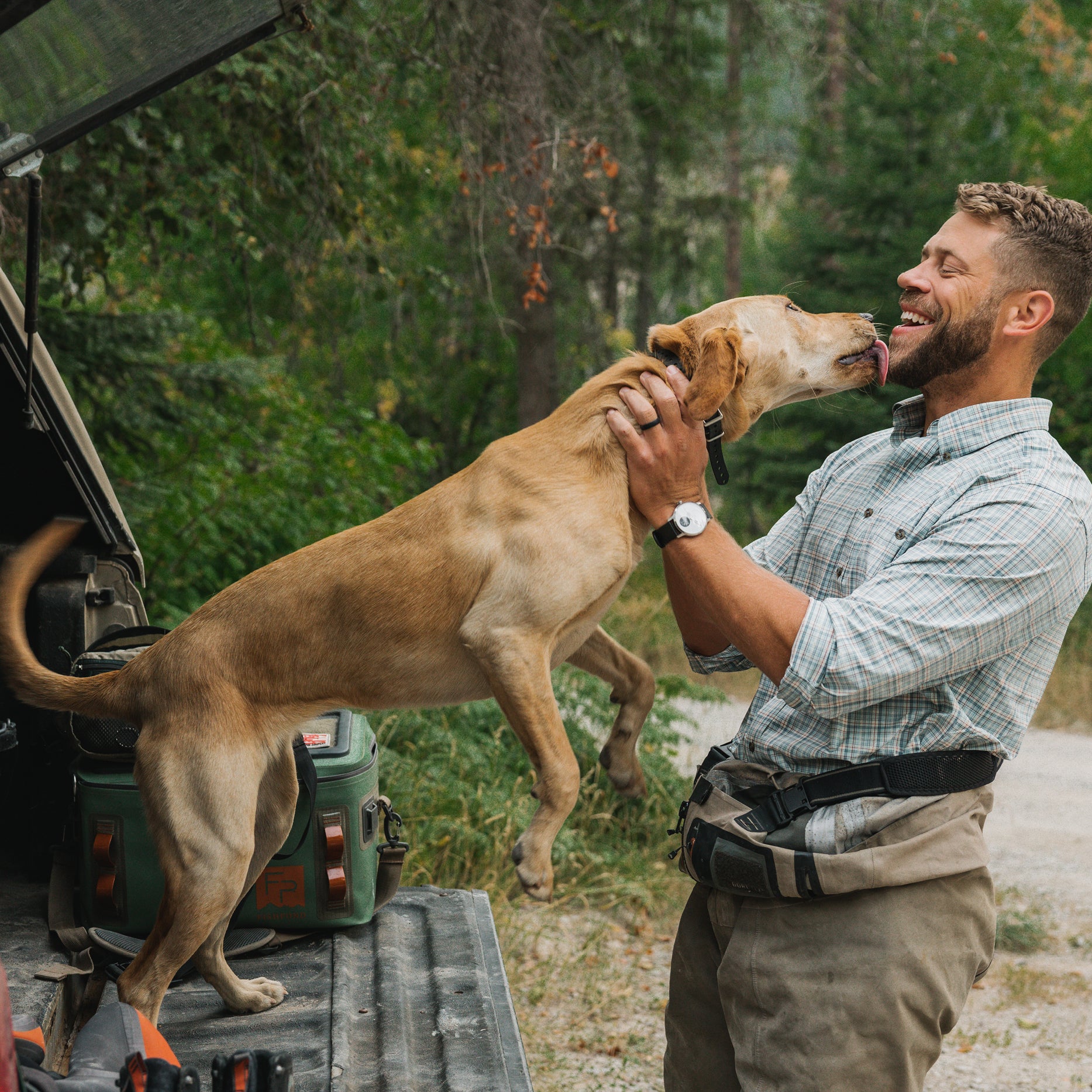 Man playing with a dog in GenTeal clothing.